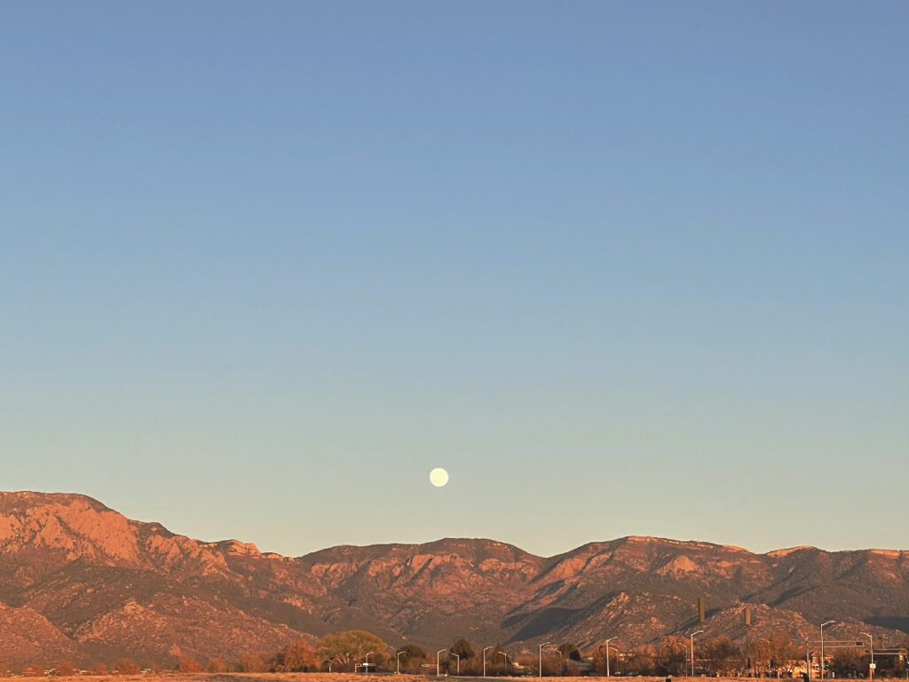 The moon rising over the mountains in Albuquerque, symbolizing Korean cultural traditions