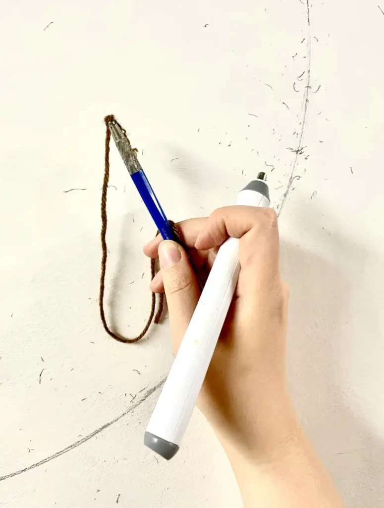 Hand of artist Bohwa Kim holding a pencil and an electric eraser